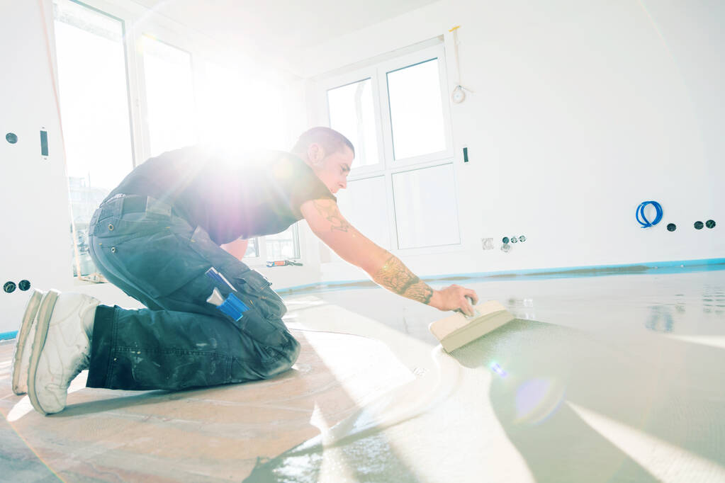 Man during floor covering working with self-levelling cement mortar
