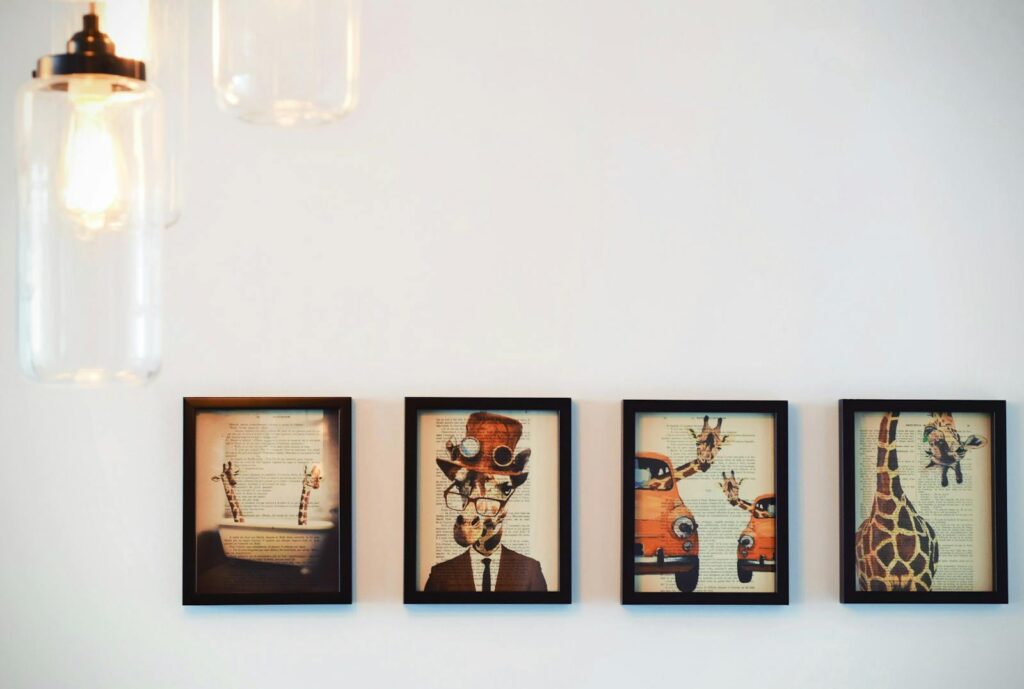 A modern interior display of four framed giraffe-themed artworks, enhanced by warm lighting.